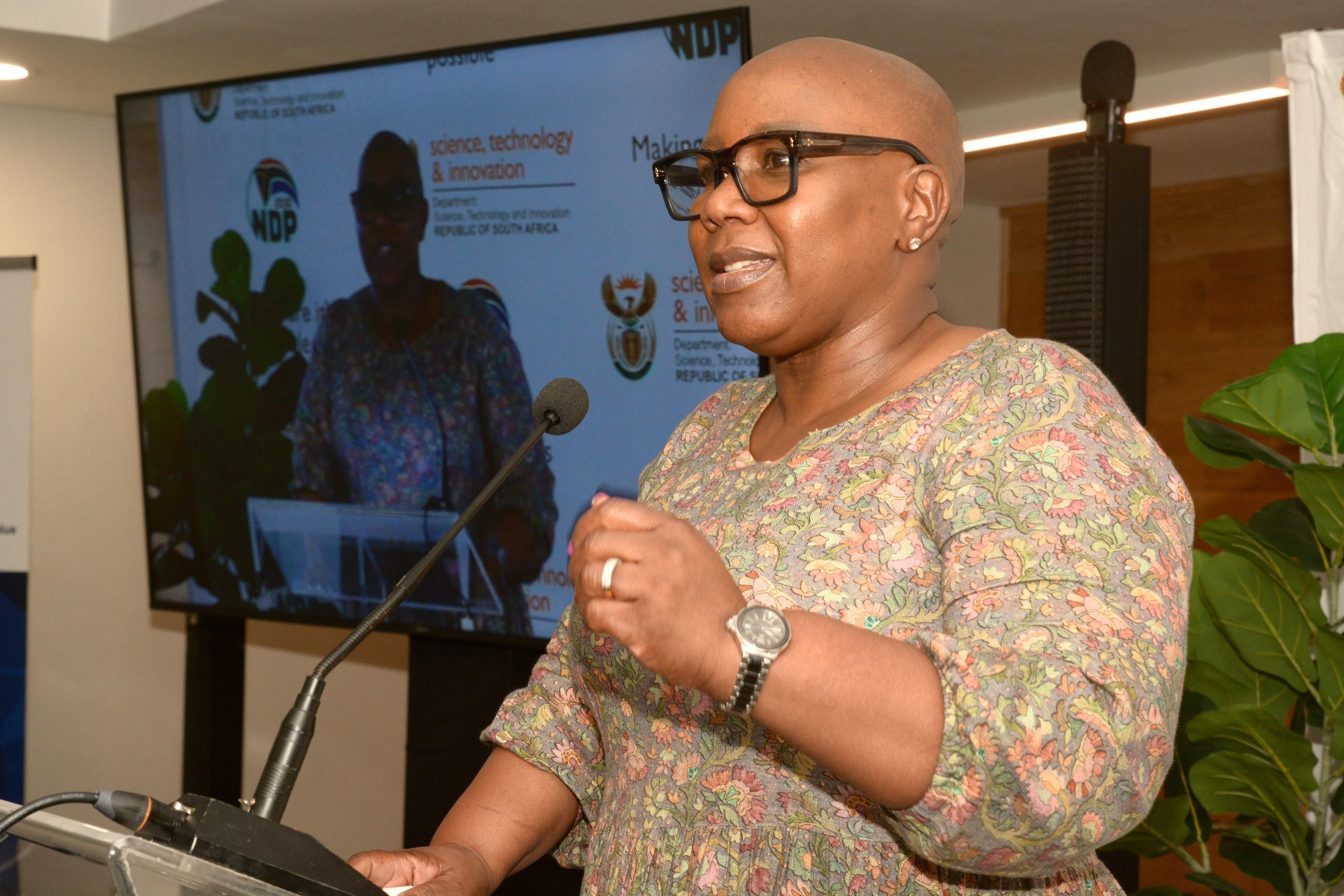 Deputy Minister Dr Nomalungelo Gina addresses delegates from a lectern at the 2026 uYilo e-Mobility Summit at Nelson Mandela University, with a DSTI-branded screen behind her.