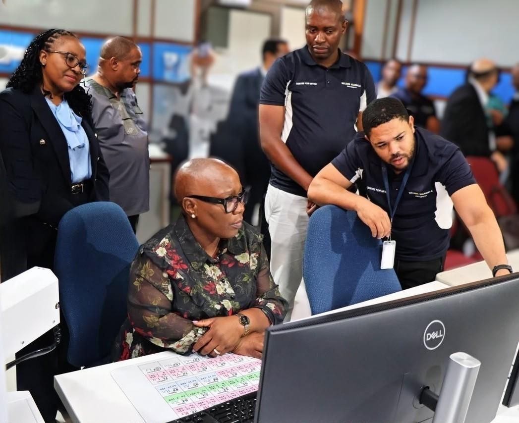 Officials and researchers gather around a computer workstation displaying microscopy data at the Centre for High Resolution Transmission Electron Microscopy